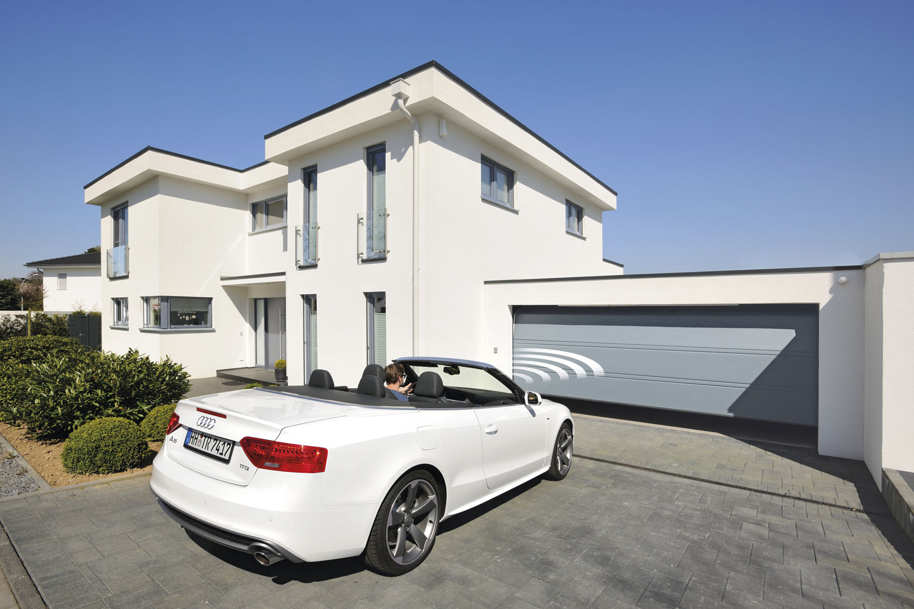 Ein graues Garagentor öffnet sich durch Betätigung des Sensors automatisch.