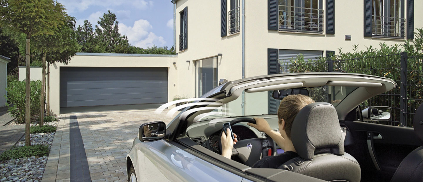 Ein Mann in einem Auto löst den Sensor aus, das automatische Garagentor öffnet sich.
